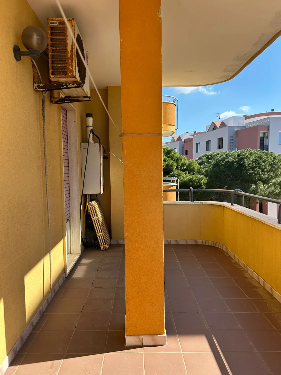 Il balcone prima dei lavori, con pavimento in cotto, pilastro giallo e caldaia a muro