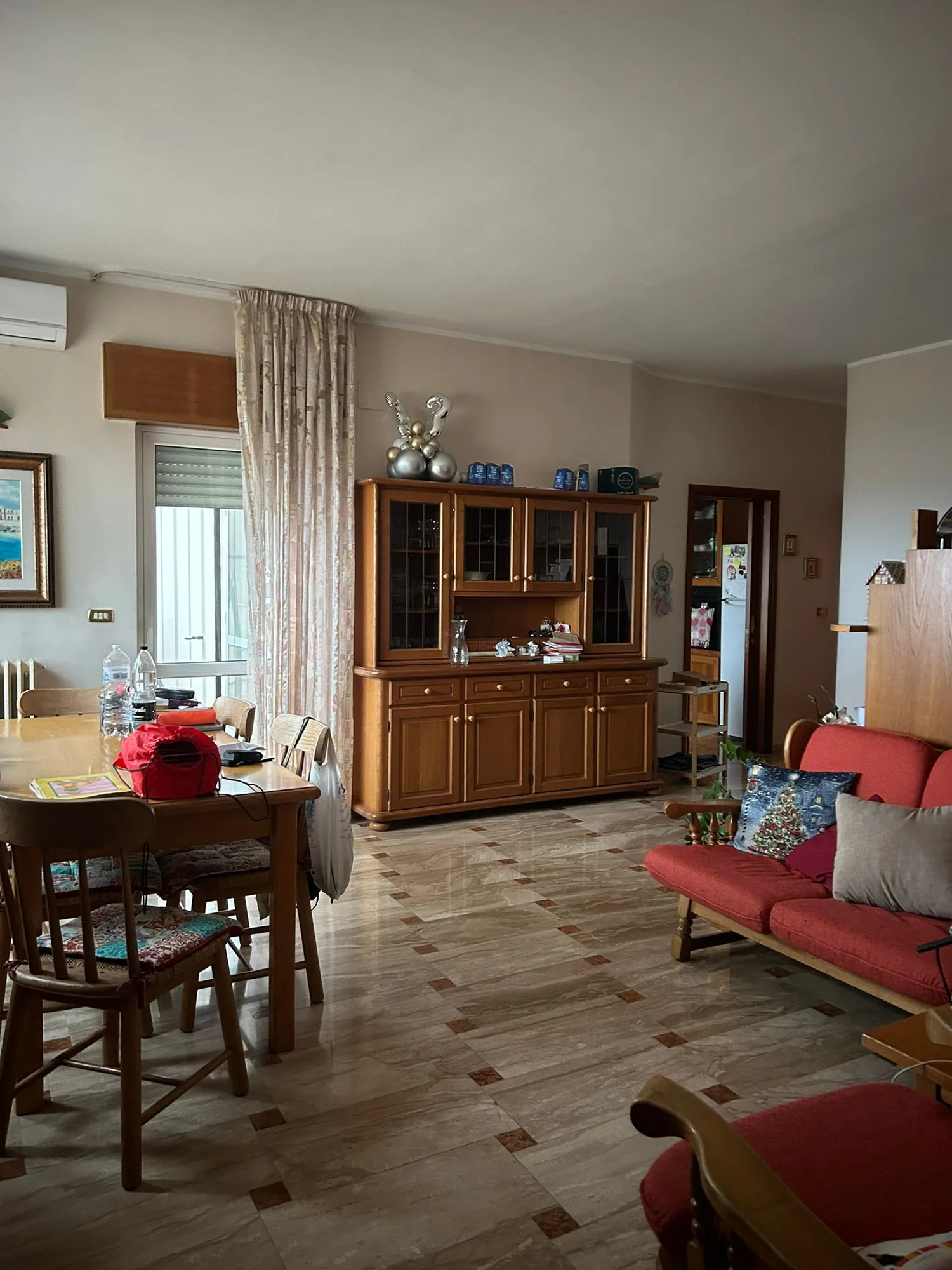Dining area before work, with wooden sideboard and red sofa