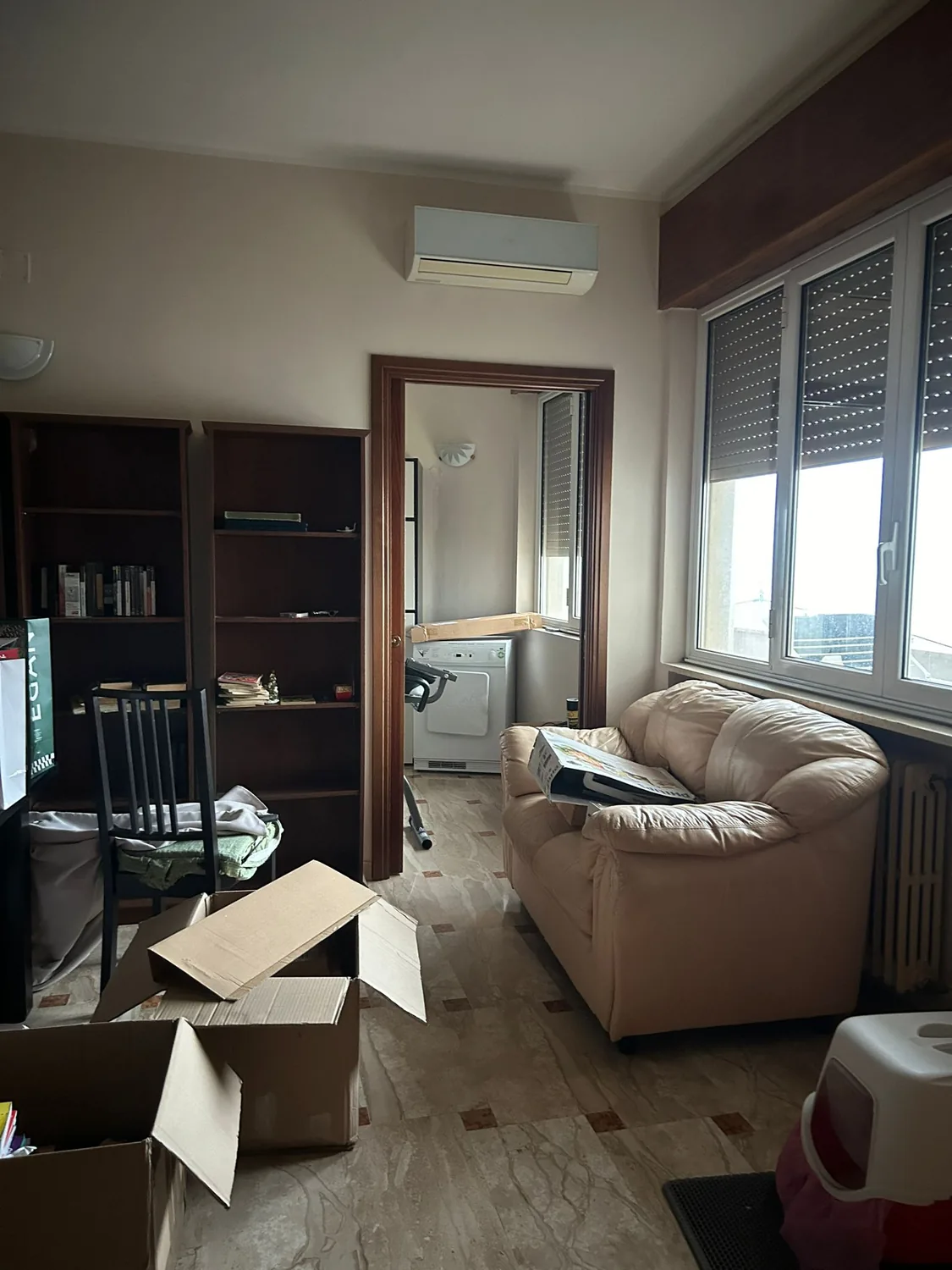 La zona giorno prima dei lavori, con pavimento originale, divano chiaro e librerie scure