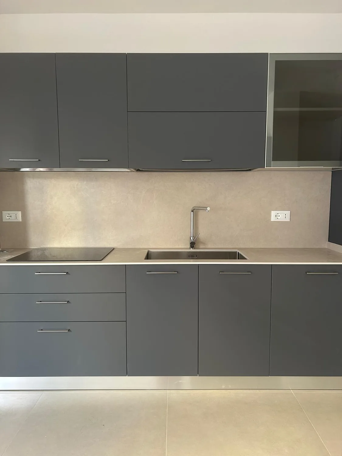 La nuova cucina, con mobili grigio scuro, lavello in acciaio e piano a induzione