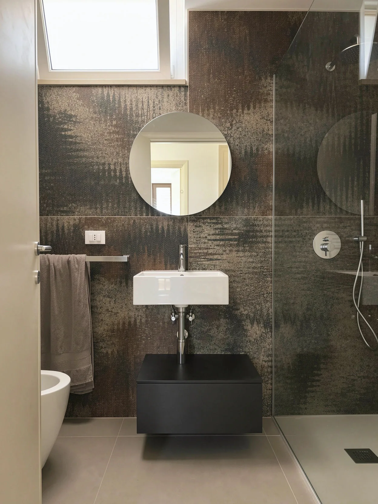 The bathroom once the work has been completed, with a suspended sink and round mirror
