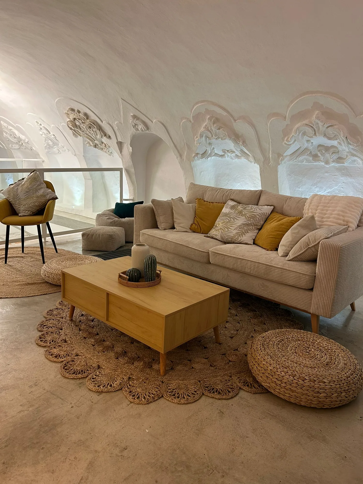 The living room finished under stucco, with a yellow table and natural fiber carpets