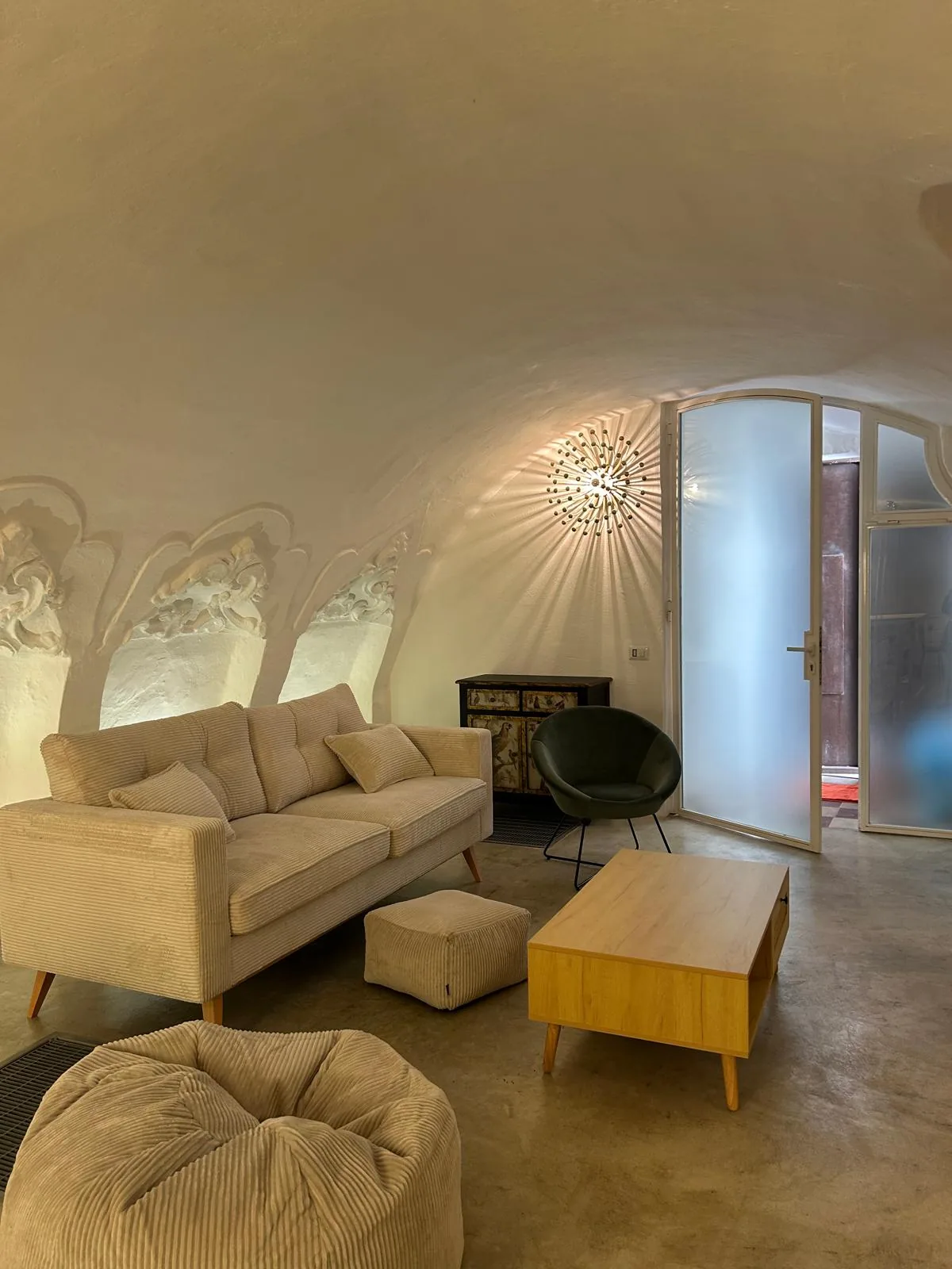 View of the living room towards the exit, with pouf and low seats