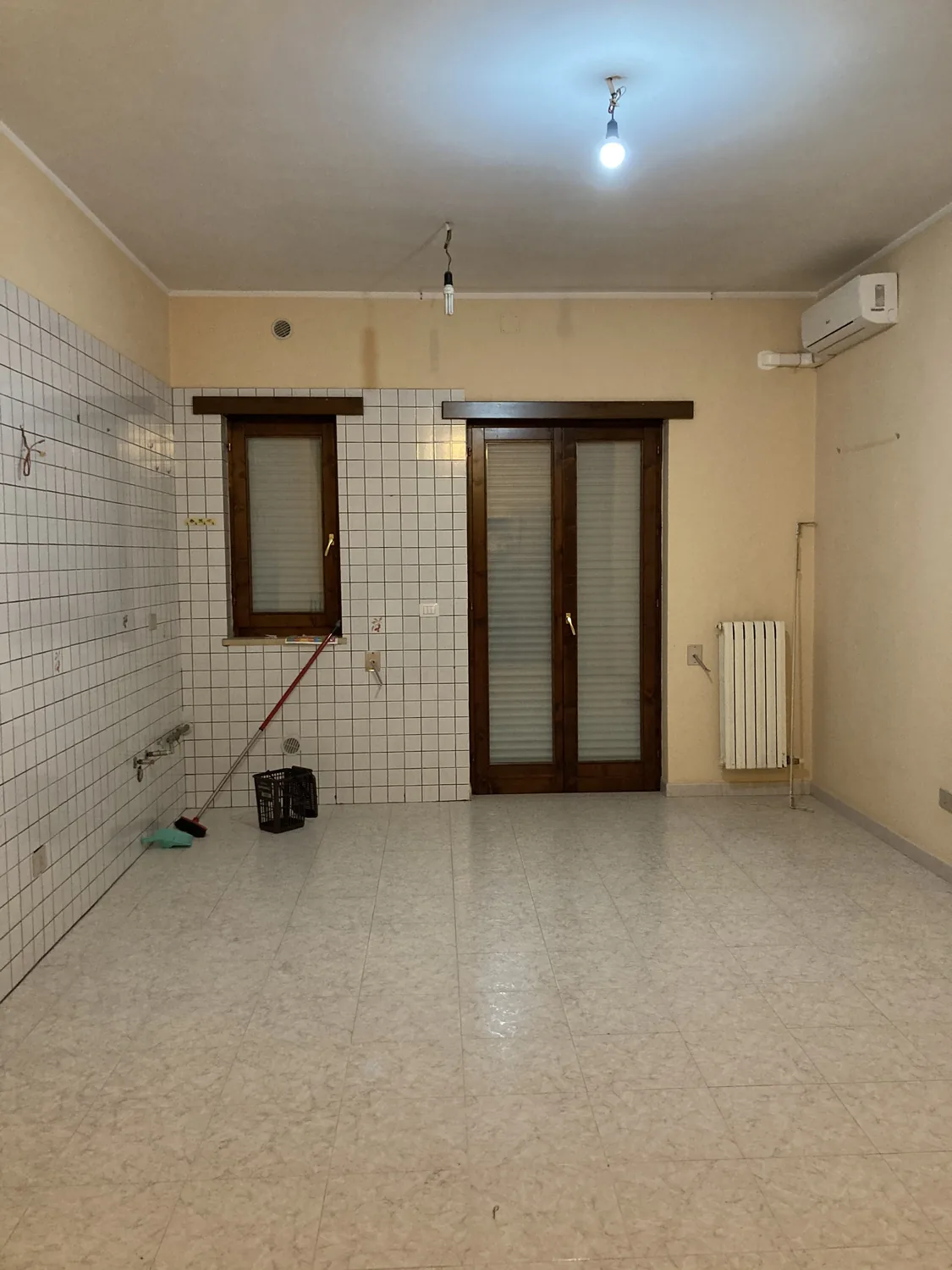 La vecchia cucina prima dei lavori, con rivestimento a quadretti, infissi in legno e calorifero