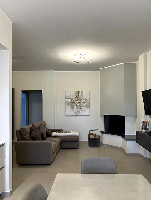 Das neue Wohnzimmer mit grau verkleidetem Eckkamin und Ecksofa