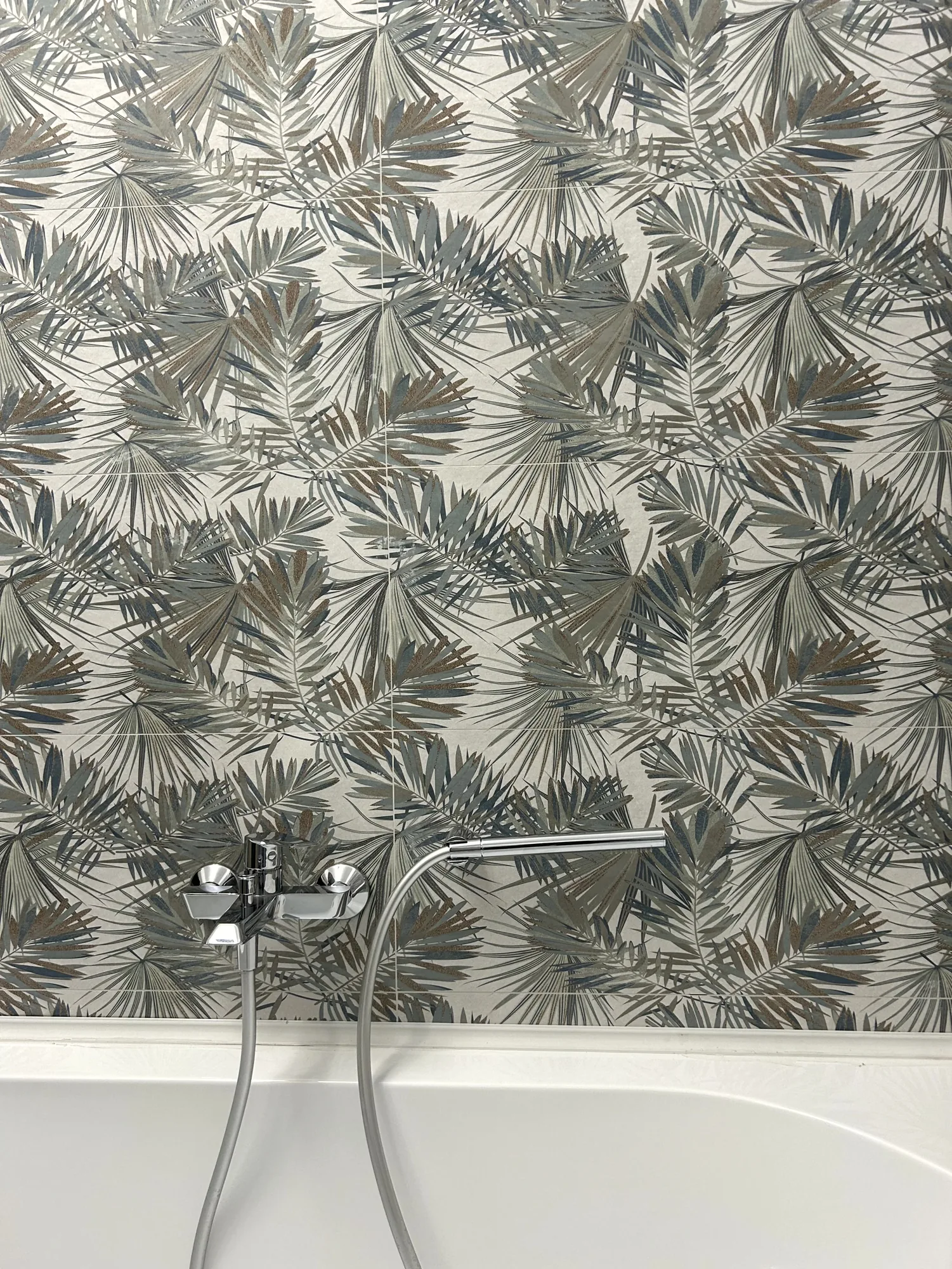 Badezimmer mit Badewanne und botanischer Motivverkleidung an der Rückwand