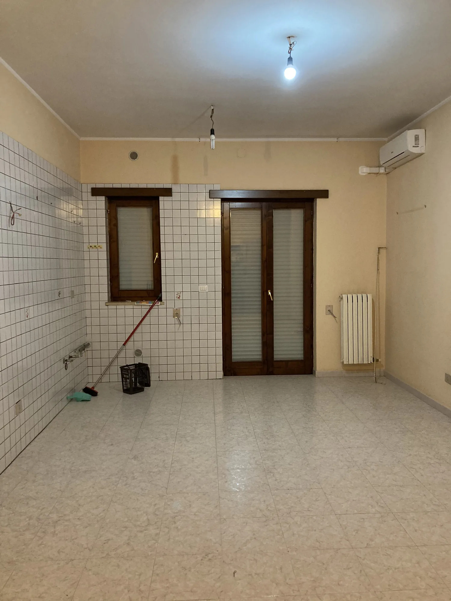 Wohnbereich vor den Arbeiten, mit weiß gefliester Wand und altem Holzfensterrahmen