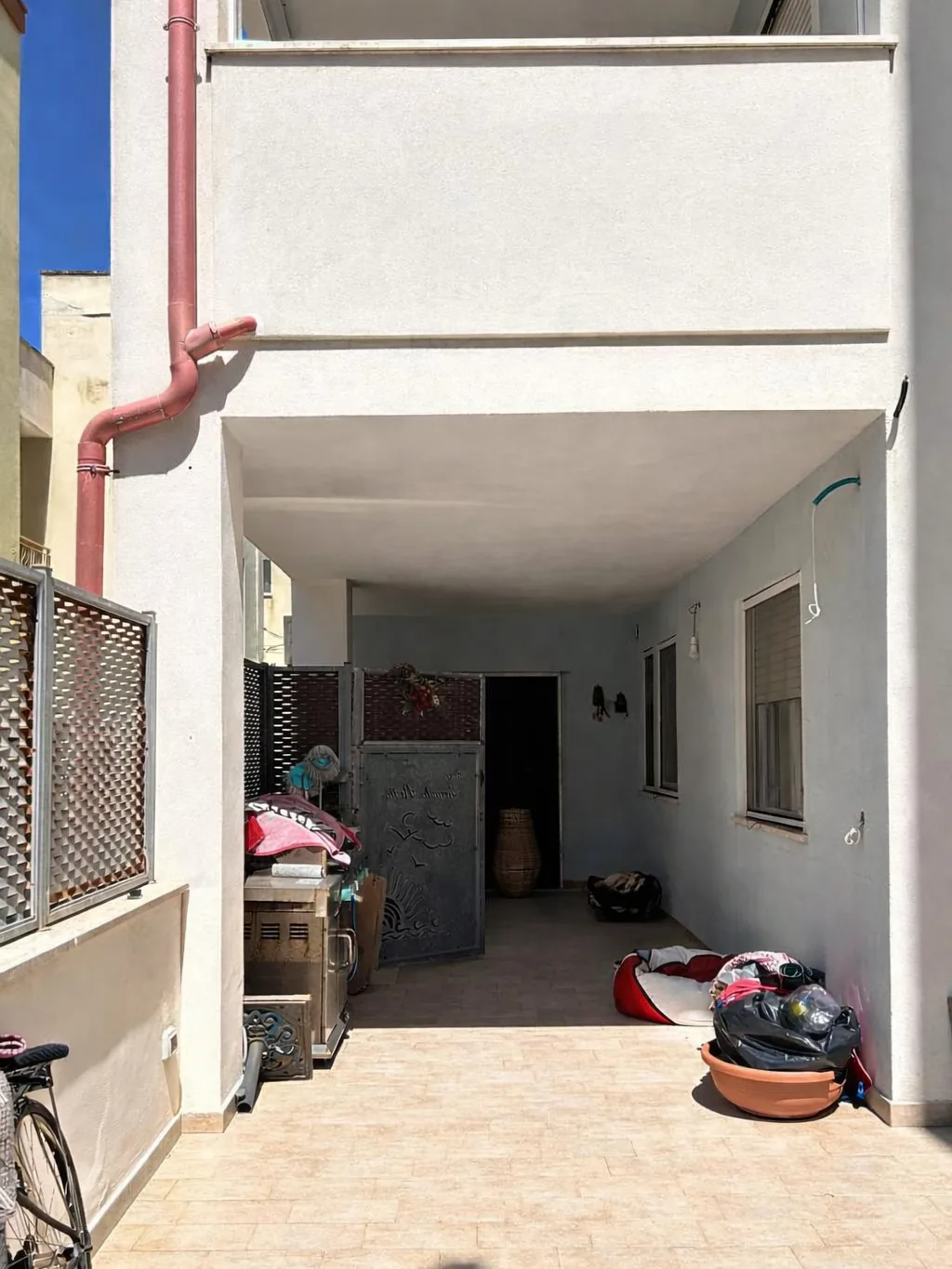 The external space before the intervention, used as storage under the portico