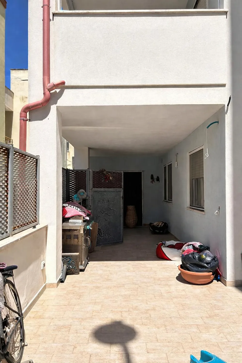 La porzione coperta del terrazzo prima dei lavori, con vasi e oggetti accatastati