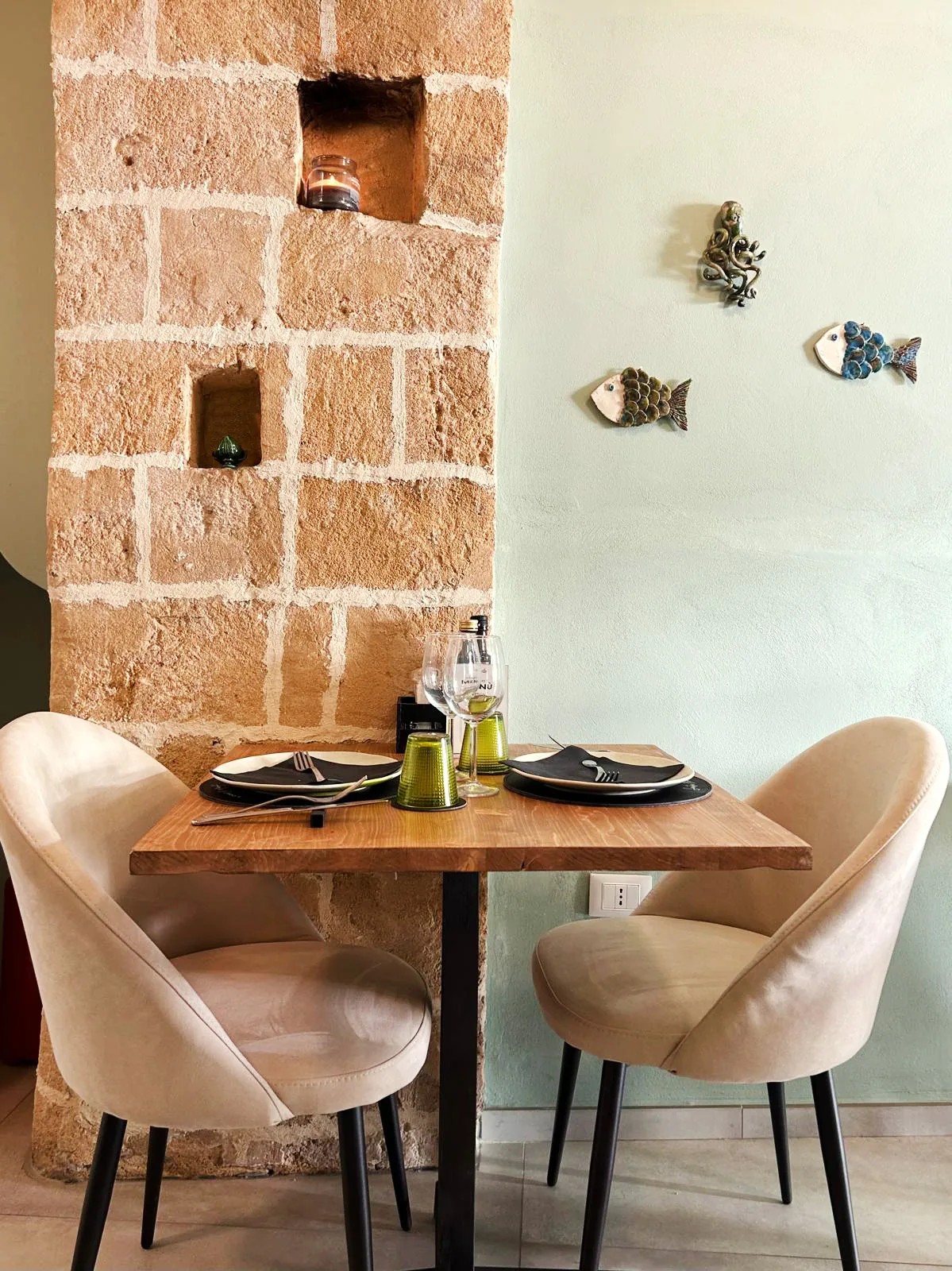 Table placed next to the stone wall, with sand-colored seats